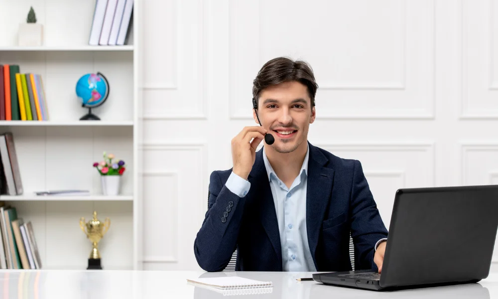 A man using microphone and laptop sitting in a table - Contact Us